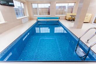 A clear blue indoor pool with mosaic tile, kept clean and ready to swim in